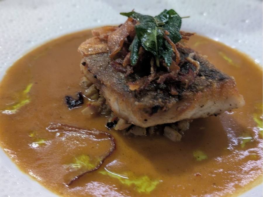 Gulai Ayam: crisp-skinned barramundi in a golden curry sauce topped with fried herbs.