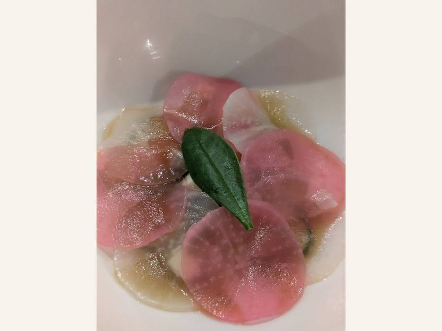 Otsumami: translucent pink radish slices in a shallow bowl with a single green leaf.