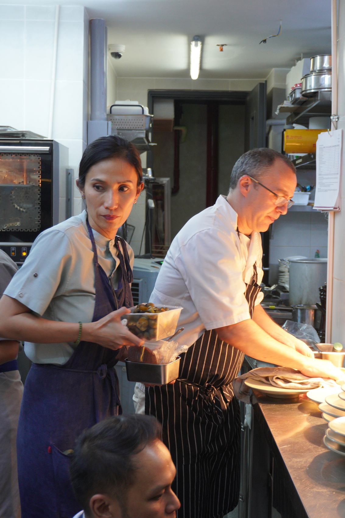 Chef Rhea Rizzo and Chef Carlos Garcia working side by side in the kitchen.